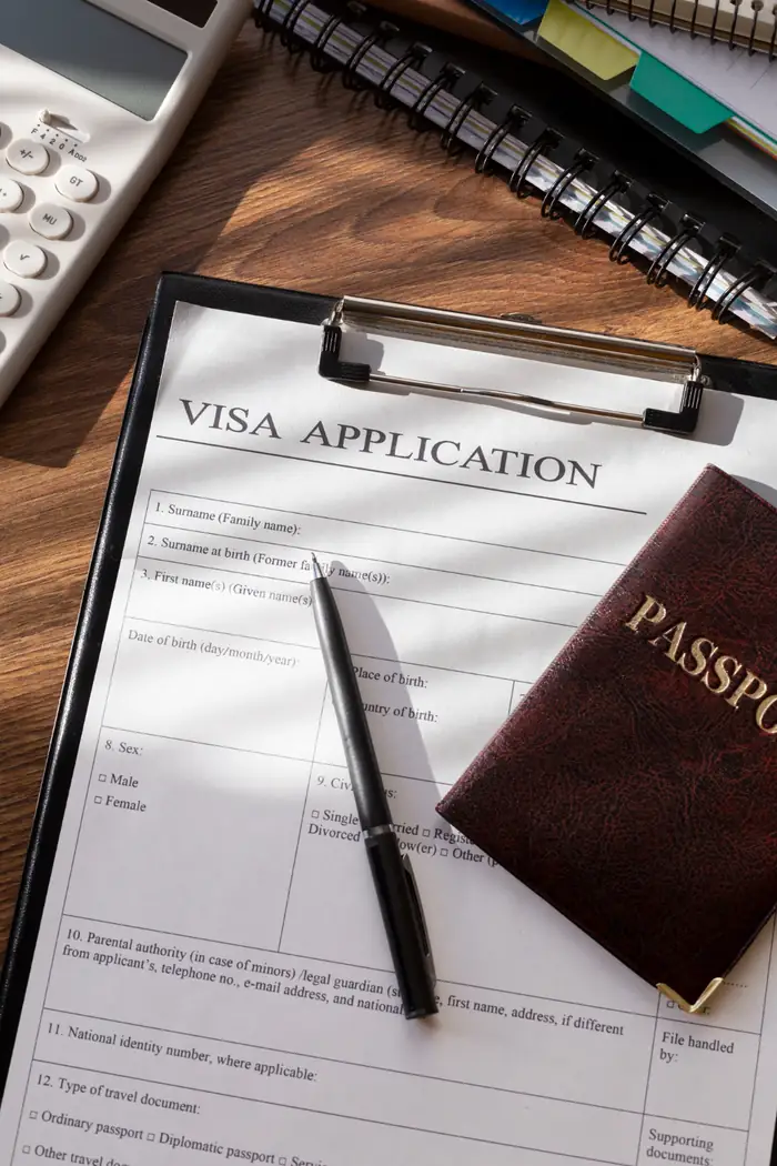 Una solicitud de visa sobre una tablilla con sujetapapeles junto a un pasaporte y un bolígrafo